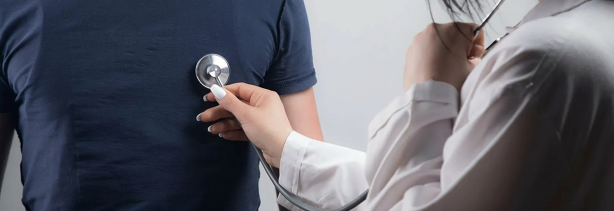 Profissional de saúde usando estetoscópio para examinar o peito de um paciente vestido com camiseta azul.